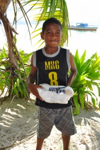 Young boy picking up batteries on beach after he heard the presentation. 