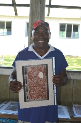 Local artist holds up art print from Solomon Islands, Marovo Lagoon, Bareho Village.