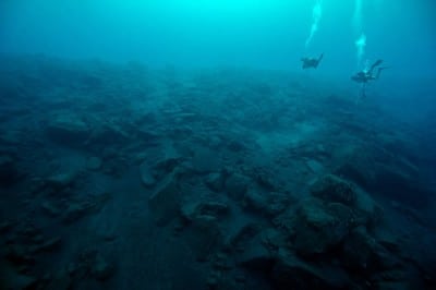 Science divers survey the underwater landscape under Tinakula, barren from the most recent eruption.