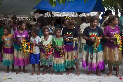 Women and children preparing to give us flower headdresses and necklaces.