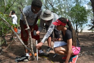 Students create the first corner of their square plot by hammering a PVC pipe into the ground.