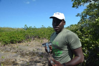 Forest Heights Academy 12th grade Marine Biology student collects a soil sample from his group's quadrat.